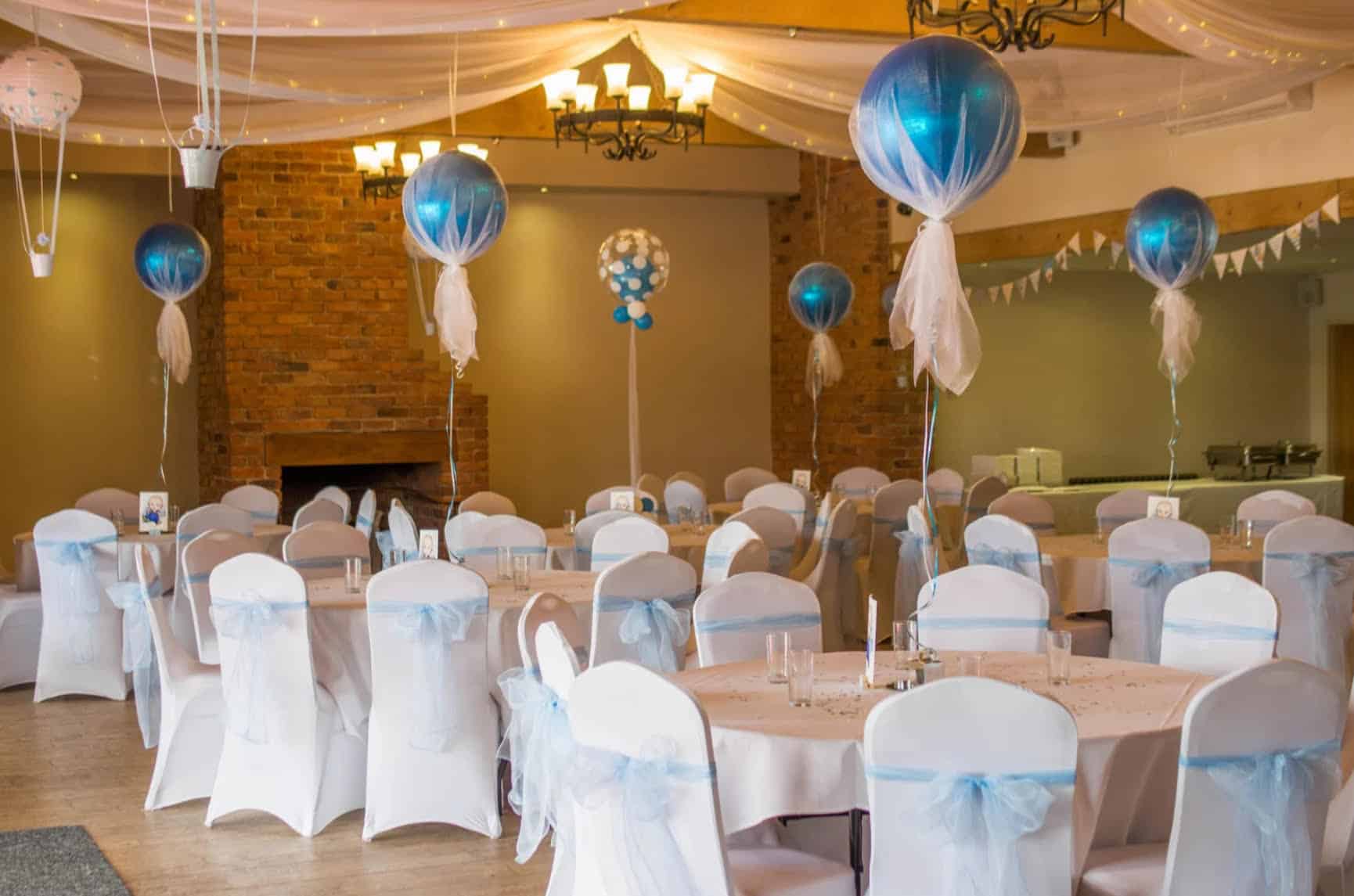 Une salle de réception élégamment décorée avec des ballons bleus, des nappes blanches et des chaises habillées.